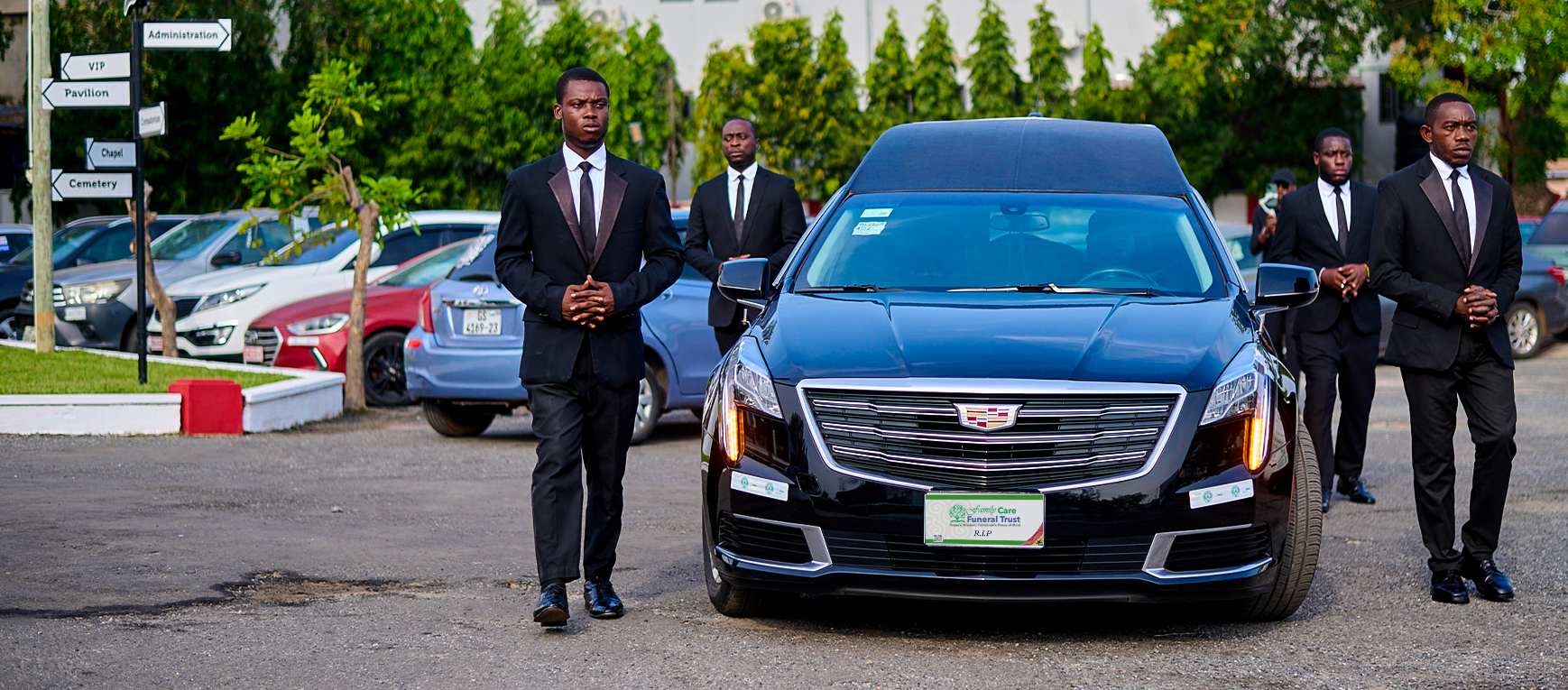 FamilyCare attendants standing with a hearse at a funeral procession